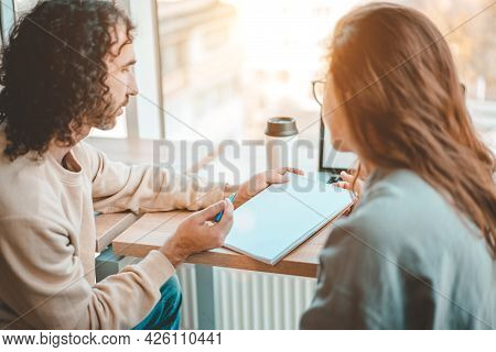 Man And Woman Discussing Business Plan At Office Workplace. Man Holding Notepad, Expaining Corporate