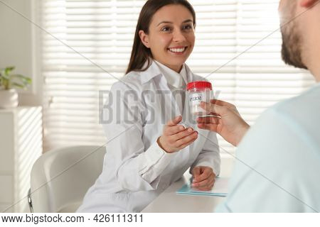 Donor Giving Container Of Sperm To Doctor In Hospital