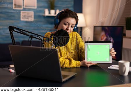 Influencer Holding Tablet With Green Screen And Speaking Into Microphone During Podcast In Home Stud