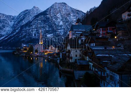 View Of Beautiful Hallstatt Lake And Famous Church During Late Evening After Sunset In Early Spring 