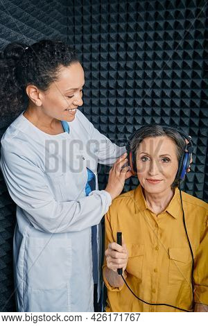 Audiometry. Audiologist Doing Hearing Exam To A Mature Woman In Soundproof Audiometric Cabin. Pure T