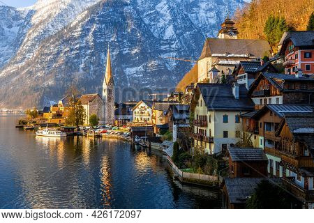 View Of Beautiful Hallstatt Lake And Famous Church During Morning Sunrise In Early Spring With Mount