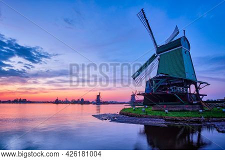 Netherlands rural scene - windmills at famous tourist site Zaanse Schans in Holland on sunset with dramatic sky. Zaandam, Netherlands