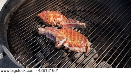 Pork Chop With Bones On On A Round Charcoal Grill. Close Up With Short Depth Of Field.
