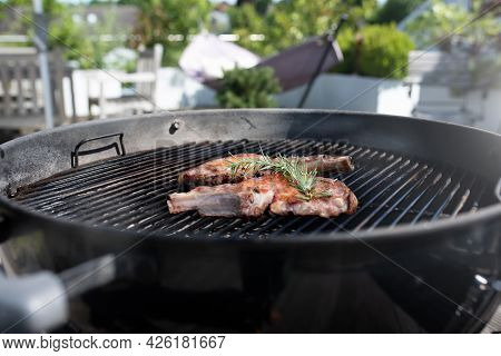 Pork Chop With Bones On On A Round Charcoal Grill. Close Up With Short Depth Of Field.