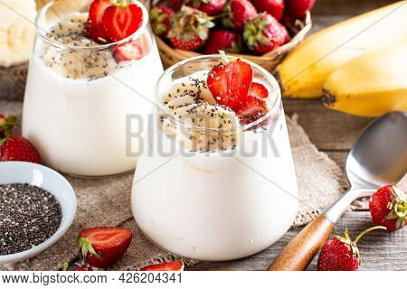 Dessert With Strawberries, Banana, Chia Seeds, Served In Glass Jars On A Wooden Table, Selective Foc