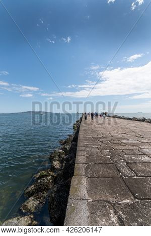 People Walk On Hte Great South Walk At Pollbeg Lighthouse.