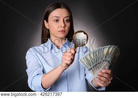 Expert Authenticating 100 Dollar Banknotes With Magnifying Glass Against Dark Background. Fake Money