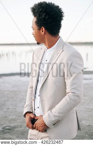 A Handsome Dark-skinned African American Man In A Light Suit With His Bright Red Cabliolet Car. The 