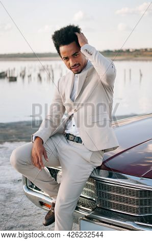 Young Black Man In Nature Posing With A Convertible. Sunset Portrait.