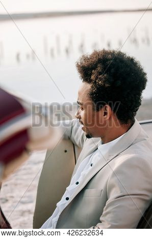 Young Black Man In Nature Posing With A Convertible. Looking Into The Distance