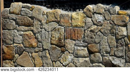 Bricklayers Tiling The House With Sandstone Stones. They Connect Stones With Cement. Behind The Clad