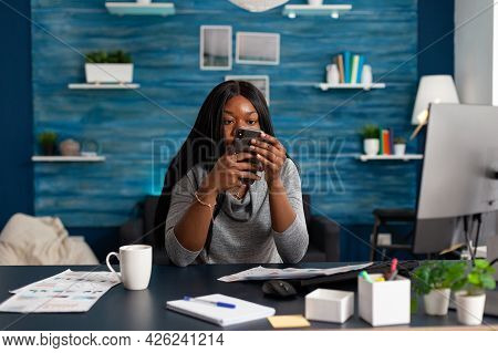 Black Student Looking Into Camera While Socializing With Friends Group Typing Message On Modern Smar