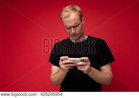 Photo Of Handsome Concentrated Upset Dissatisfied Young Blonde Man Isolated Over Red Background Wall