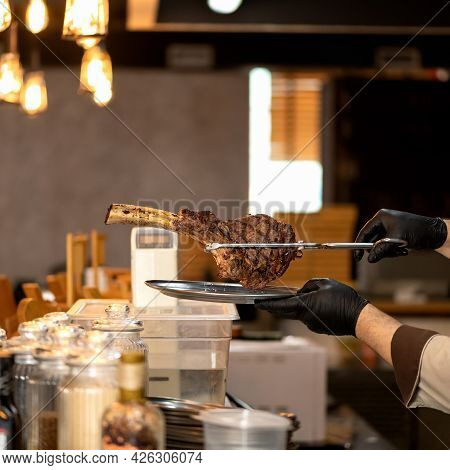 Chef Holding Meat Steak Ribeye. Person In Black Disposable Gloves Holds Grilled T-bone Or Tomahawk S