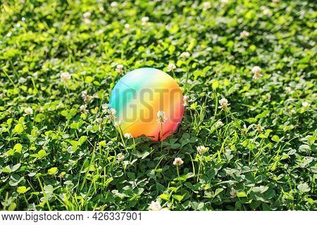Rainbow Colored Kids Ball On A Lawn On In A Backyard. Children Toys, Outdoor Leisure And Summer Time