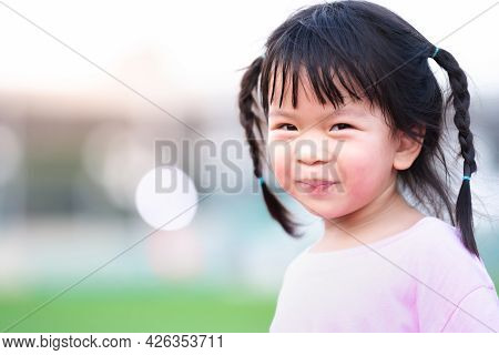 Portrait Of Asian Face Child Girl Sweet Smile. Happy Kid With Blurred Bokeh Background In The Evenin