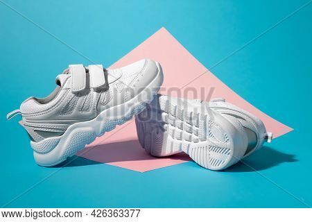 Macro Side View One White Childrens Running Shoe Stands On The Sole Of A Second Running Shoe Lying O