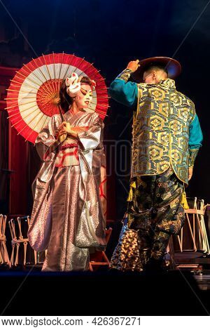 Japanese Woman Geisha In Traditional Kimono And  Meets And Kino Kitsune Fox Mask Greets Man In A Dar