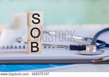 The Word Sob Is Written On Wooden Cubes Near A Stethoscope On A Paper Background. Sob - Short For Sh