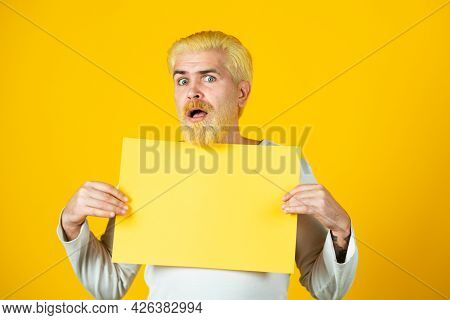 Man Holding A Blank Sheet Of Paper, Isolated On Yellow Background.