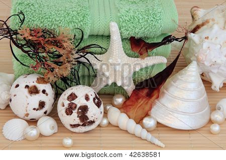 Algen Spa Zubehör mit Bad Bomben, Handtücher, Muscheln und Perlen über Bambus Hintergrund.