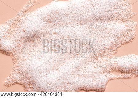 Face Cleansing Mousse Sample. White Cleanser Foam Bubbles On Nude Background. Soap, Shower Gel, Sham