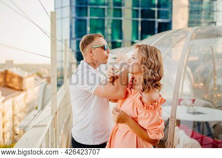 Man And Woman Drink Champagne On Bruderschaft In A Rooftop Cafe.