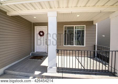 Front Porch Facade Of A House With Vinyl Wall Siding And Metal Railings