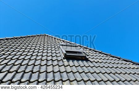 Open Roof Window In Velux Style With Black Roof Tiles.