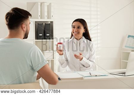 Donor Giving Container Of Sperm To Doctor In Hospital