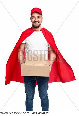 Cheerful Bearded Male Courier In Red Superhero Cloak And Cap Delivering Cardboard Boxes And Looking 