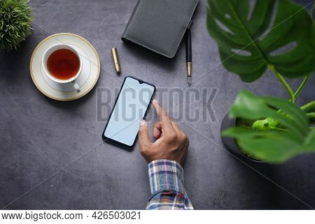 Top View Of Man Hand Using Smart Phone On Black Background
