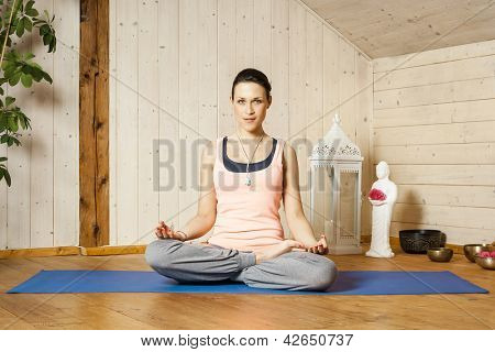 En bild av en vacker kvinna som gör yoga hemma - siddhasana