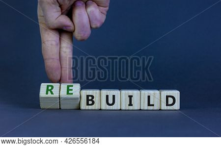 Time To Rebuild. Businessman Turns Wooden Cubes And Changes The Word Build To Rebuild On A Beautiful