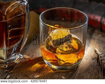 Carafe of whisky and glass of whisky on old wooden cask at the dark background.