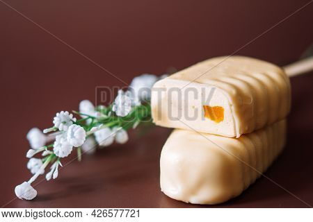 White Chocolate Popsicles Cut With Filling Lying On Top Of Each Other On Brown Background
