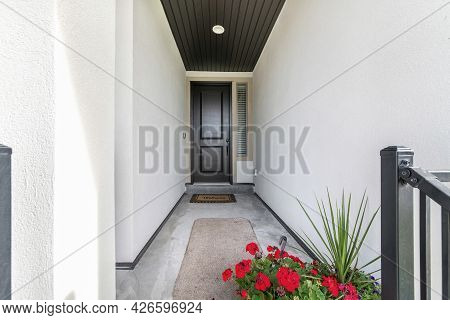 Front Door Corridor With White Walls Leading To A Wooden Door With Window Panel