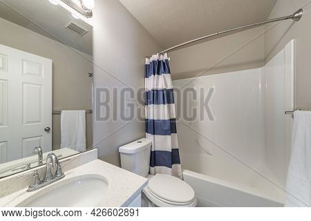 Bathroom Interior With Vanity Sink And Bathtub Shower Combo With Striped Shower Curtain