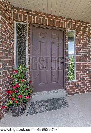 Vertical Home With Red Brick Exterior Wall And Brown Front Door Between Narrow Sidelights