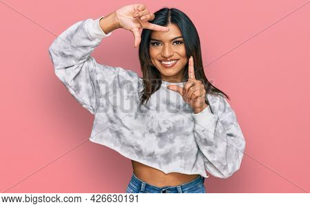 Young latin transsexual transgender woman wearing casual clothes smiling making frame with hands and fingers with happy face. creativity and photography concept. 