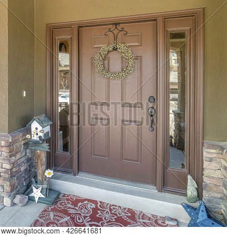 Square Brown Front Door And Sidelights At The Facade Of Home With Bench Against Window