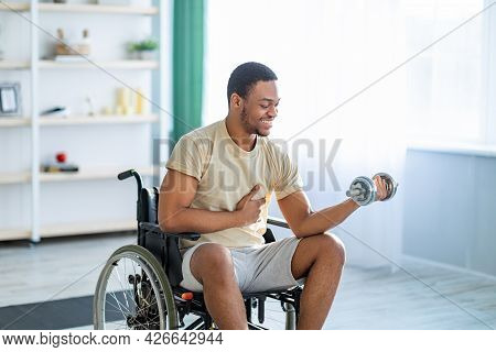 Physical Rehab For Impaired People. Positive Handicapped Black Man In Wheelchair Exercising With Dum