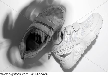 Top View Macro Two White Sneakers With Hard Summer Sun Shadows From A Monstera On An Isolated White 