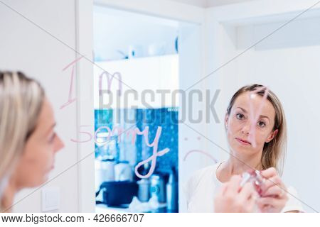 Sad Woman Writes The Words Im Sorry On The Mirror.