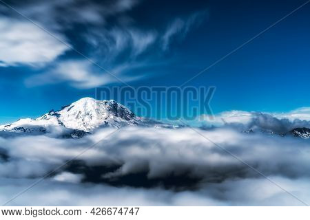 Mount Rainier In Washington Peaks Its Head Above The Wispy Clouds Below. Dramatic Rendition Of This 