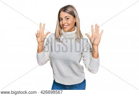 Beautiful blonde woman wearing casual turtleneck sweater showing and pointing up with fingers number eight while smiling confident and happy. 