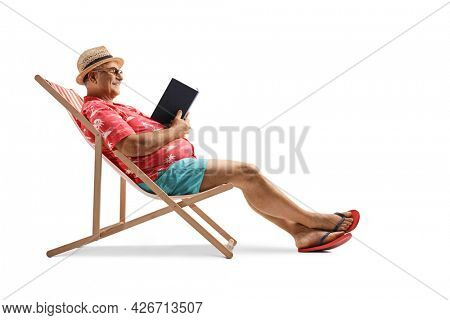 Mature male tourist reading a book and sitting in a bech chair isolated on white background
