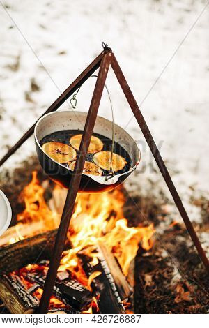 From Above Traditional Mulled Wine With Slices Of Orange Preparing In Pot Over Burning Logs In Winte