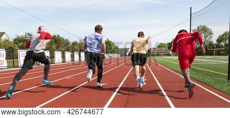 Rear View Of High School Boys Sprinting Down The Track In Lanes Racing Each Other During Practice.al